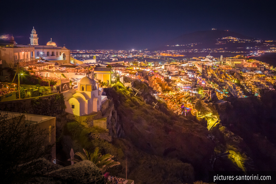 A night panorama of Fira, Santorini, with the illuminated town tracing the edge of the caldera