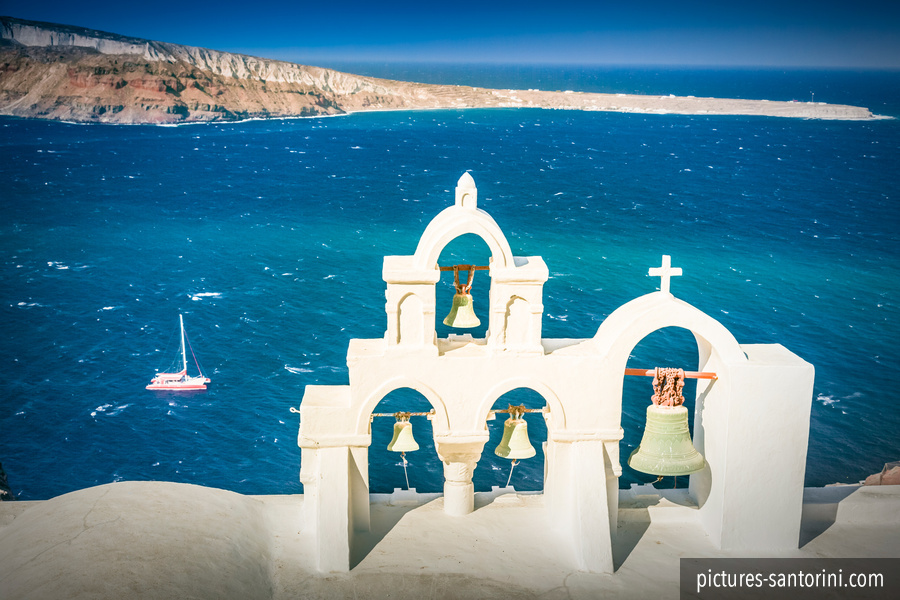 A traditional white bell tower in Oia, Santorini, set against the clear Greek sky