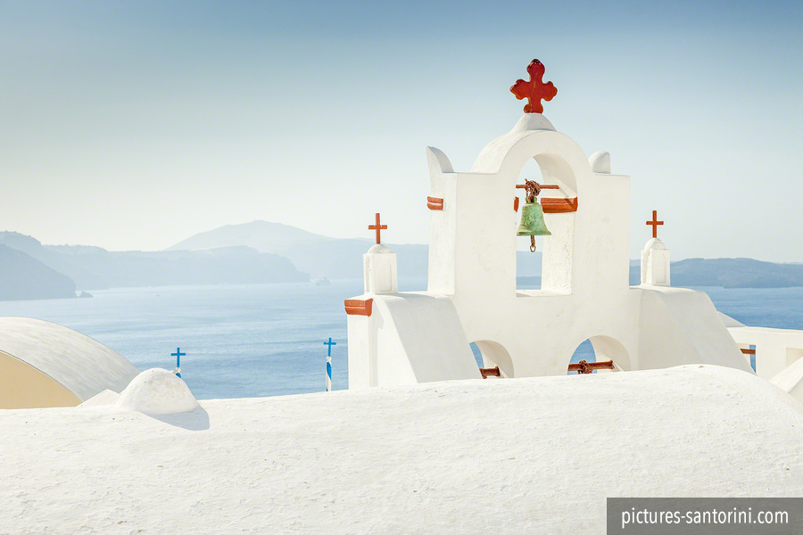 Bell tower against the morning sun in front of the caldera. This photo was taken in Oia, Santorini