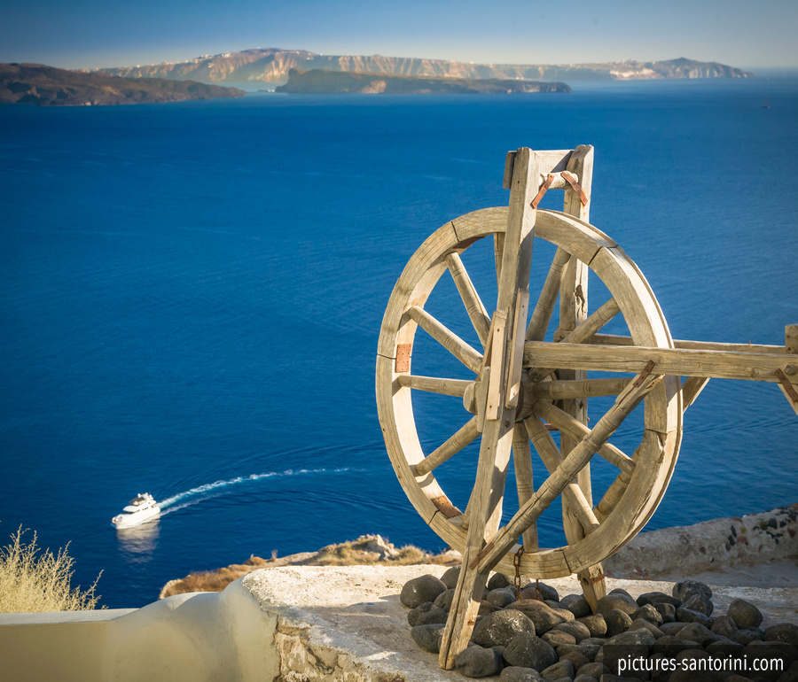 Wooden wheel in front of the caldera of the island of Santorini