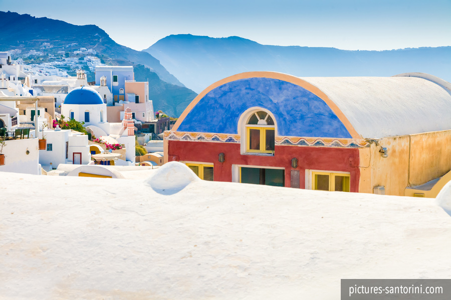 A colourful building in Oia, Santorini, overlooking the blue water and volcanic rim of the caldera