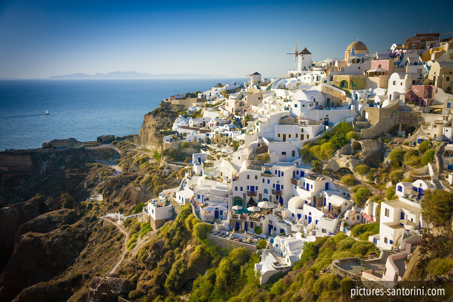Oia in the afternoon light, with white buildings layered along the northern edge of Santorini’s caldera