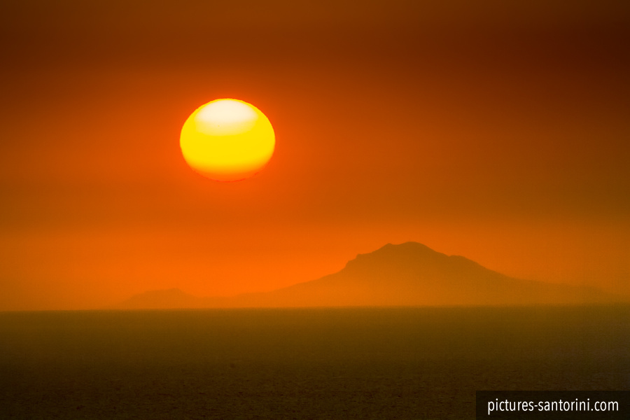 Sunset as seen from Oia, Santorini. An extreme telephoto lens has been used to take this picture. The island in the background is named Folegandros